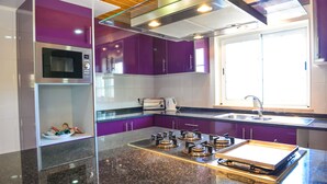 Een moderne keuken met paarse kastjes, een roestvrijstalen magnetron en een gasfornuis.