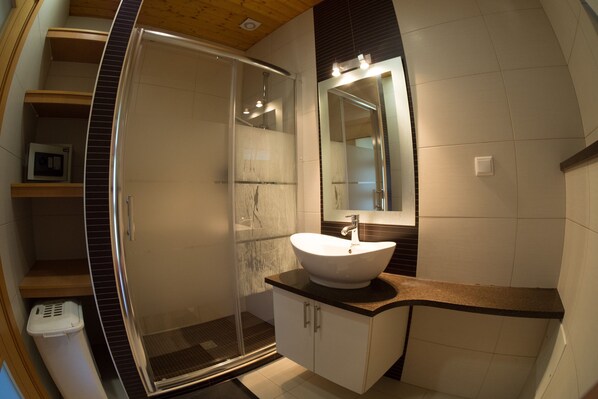 Une salle de bain moderne avec une douche à parois de verre, un lavabo blanc et un grand miroir.