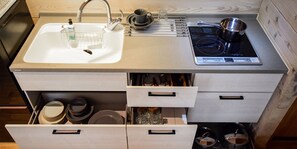 A kitchen with a sink, stove, and storage drawers. - Baan Hakuba (Hakuba)
