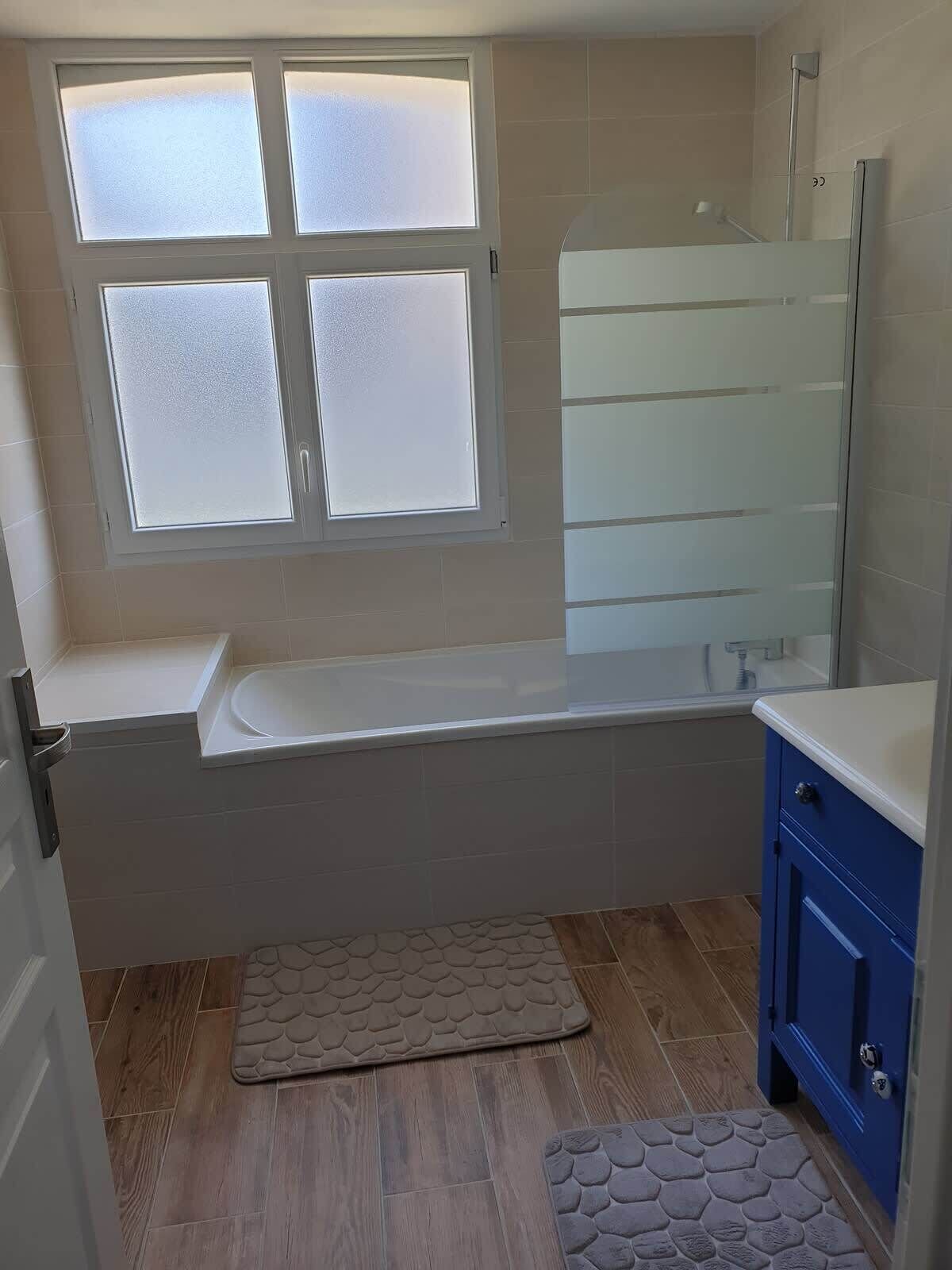 A bathroom with a bathtub, a shower, and a window.