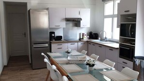 Una cocina moderna con comedor, electrodomésticos de acero inoxidable e iluminación colgante.