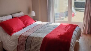 Un dormitorio con cama, lámpara y vistas al exterior.