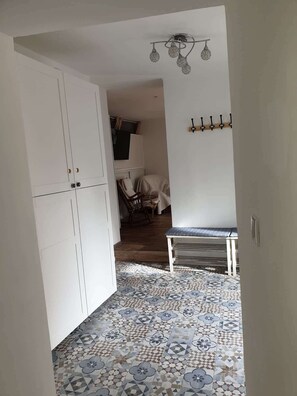 A hallway with patterned floor tiles, a white wardrobe, and a ceiling light fixture.