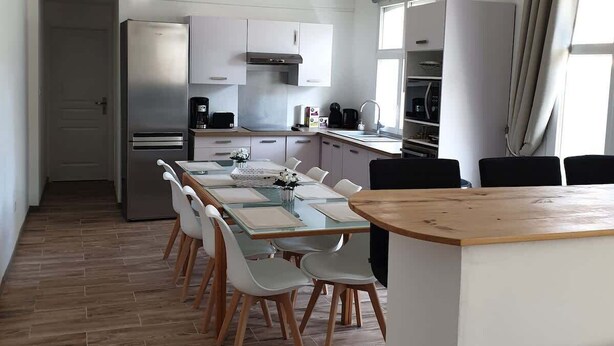 Una cocina moderna con comedor, piso de madera e iluminación colgante.
