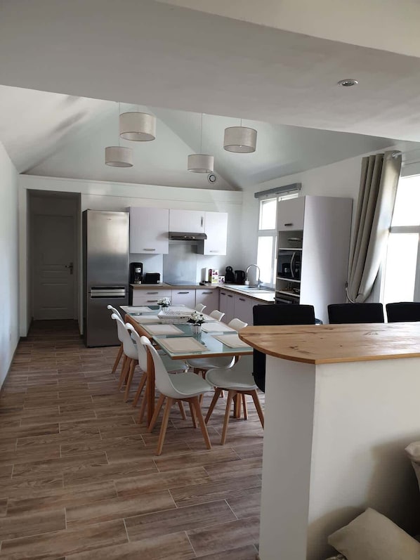 Une cuisine moderne avec un coin repas, un plancher en bois et des luminaires suspendus.