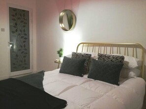 Une chambre à coucher avec un lit, un miroir rond, une petite table avec une plante et une porte décorative.