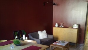 A dining area with a wooden table and chairs, a sofa, and a cabinet with kitchen items. - Private Room With Ensuite Groundfloor (Luqa)