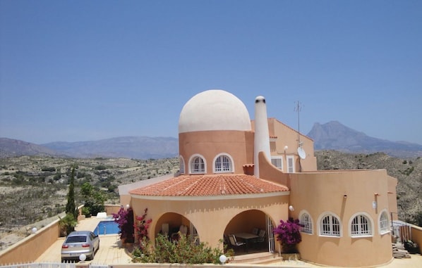 A Mediterranean-style building with a dome, arches, and a swimming pool.