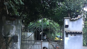 A metal gate with intricate designs, a concrete wall, and a small structure with a tiled roof. - Room-double Room With Services (San Giuliano Terme)