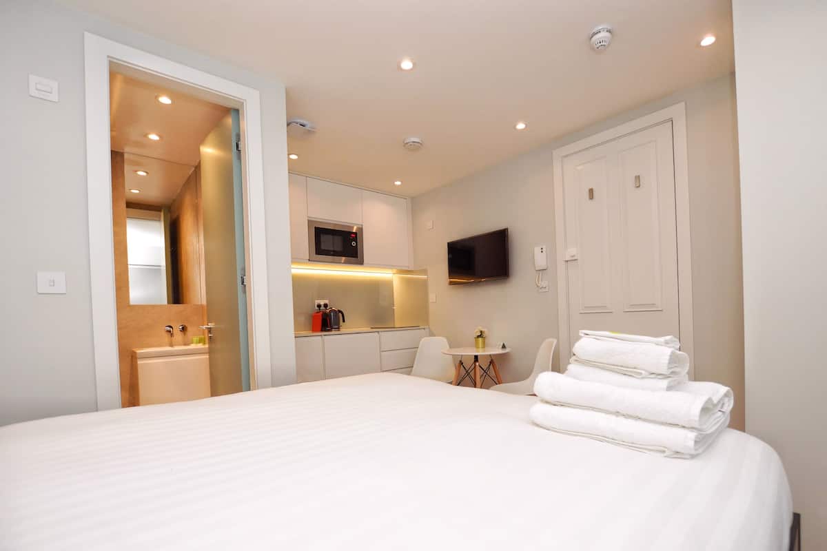 A hotel room with a bed, a TV, a microwave, and a small kitchenette.