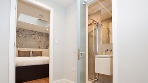Ein Schlafzimmer mit Bett, ein Badezimmer mit Dusche und eine Tür zu einem anderen Raum.