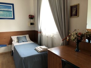 A hotel room with a bed, a desk, a vase with flowers, a painting, and a thermostat on the wall. - Venice Mestre Tourist Accommodation, Quiet Room With Wifi and Free Parking (Mestre)
