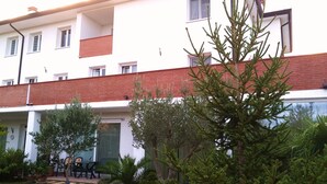 A multi-story building with a red brick facade, outdoor seating area with tables and chairs, and various potted plants. - Venice Mestre Tourist Accommodation, Quiet Room With Wifi and Free Parking (Mestre)