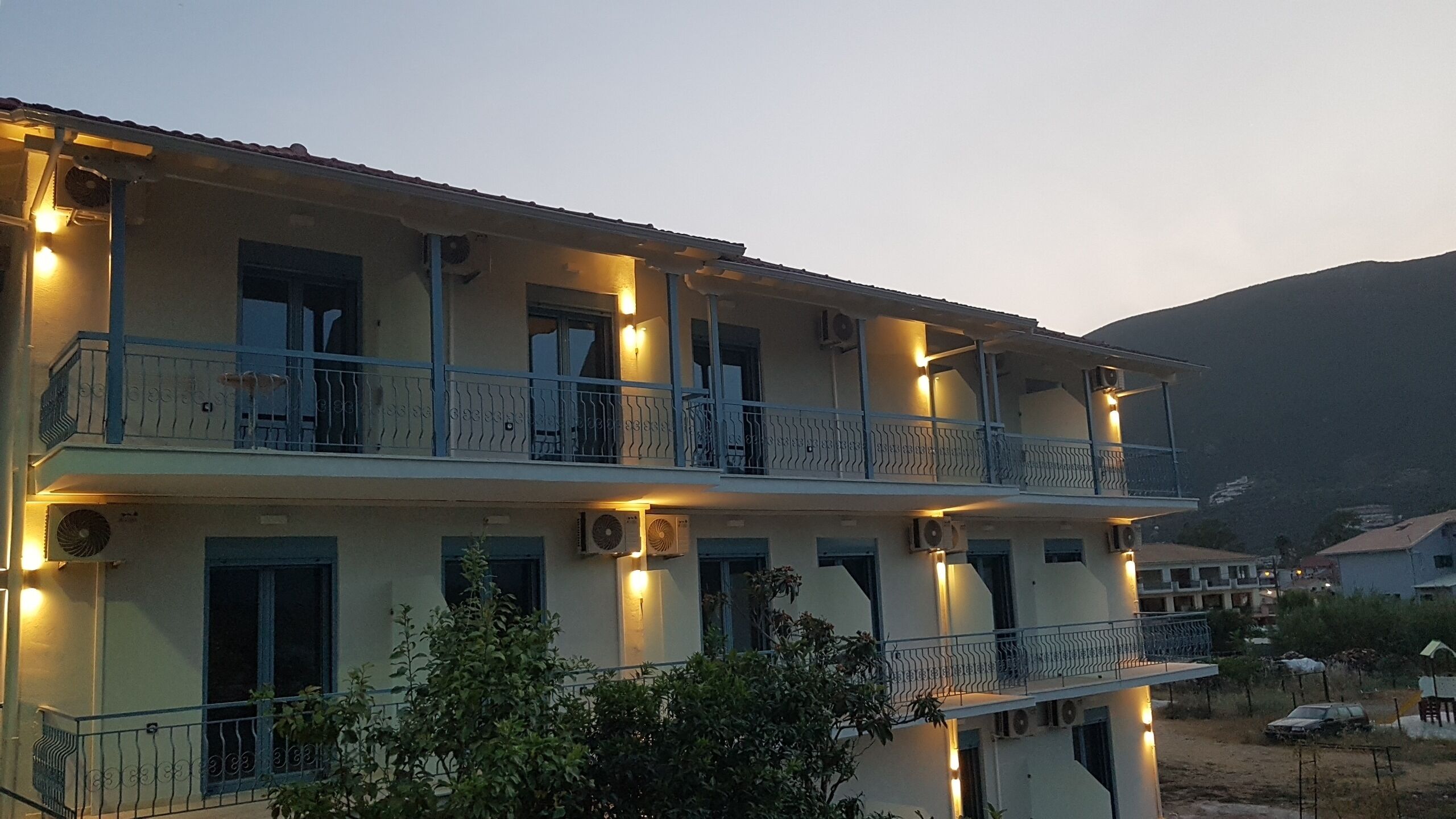 A multi-story building with balconies, air conditioning units, and outdoor lighting.