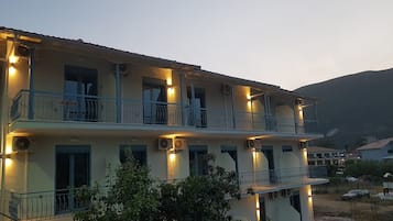 A multi-story building with balconies, air conditioning units, and outdoor lighting.