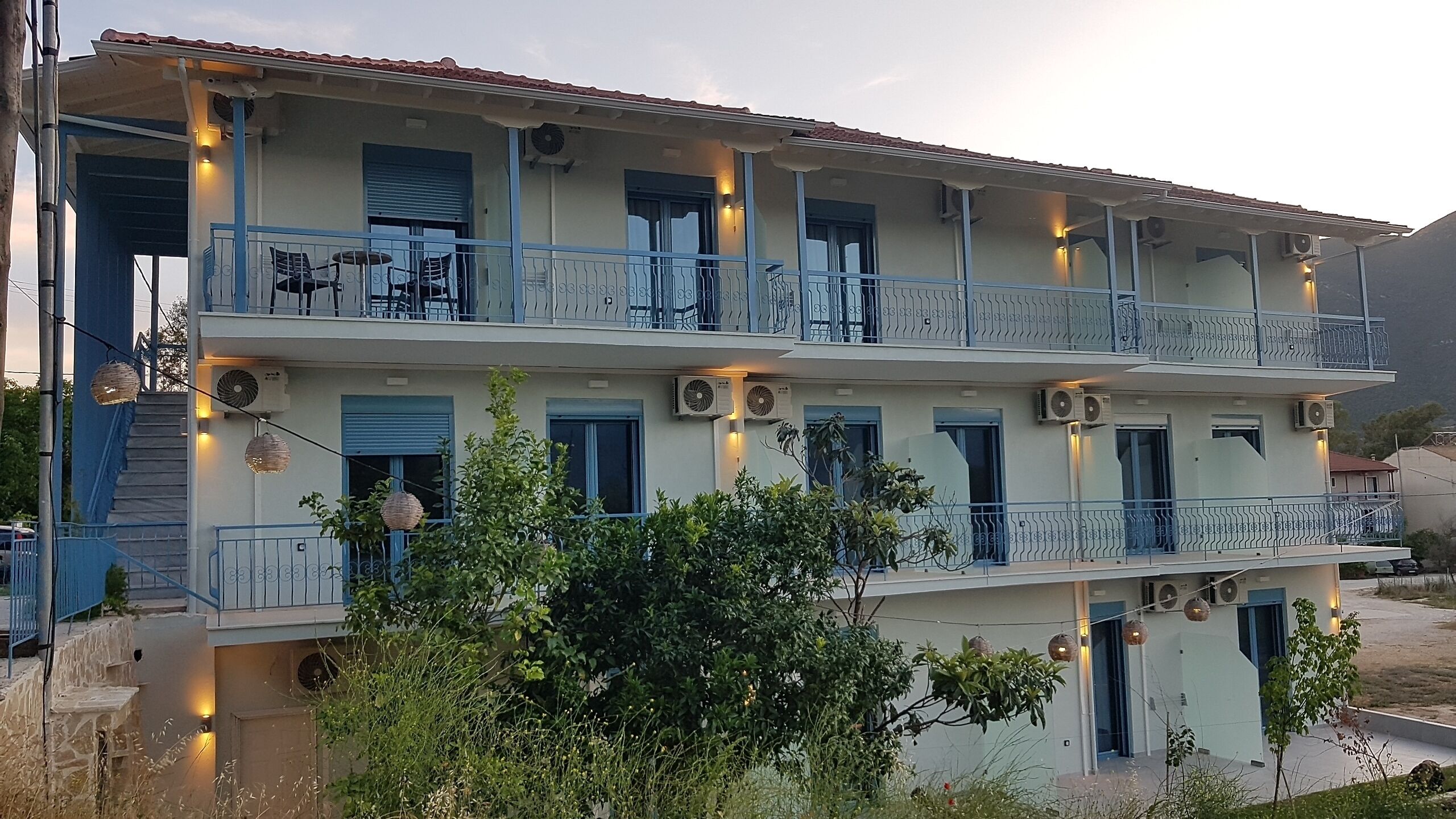 A multi-story building with balconies, air conditioning units, and outdoor seating.