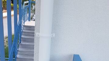 Un escalier en béton avec des rampes bleues menant à un mur blanc.