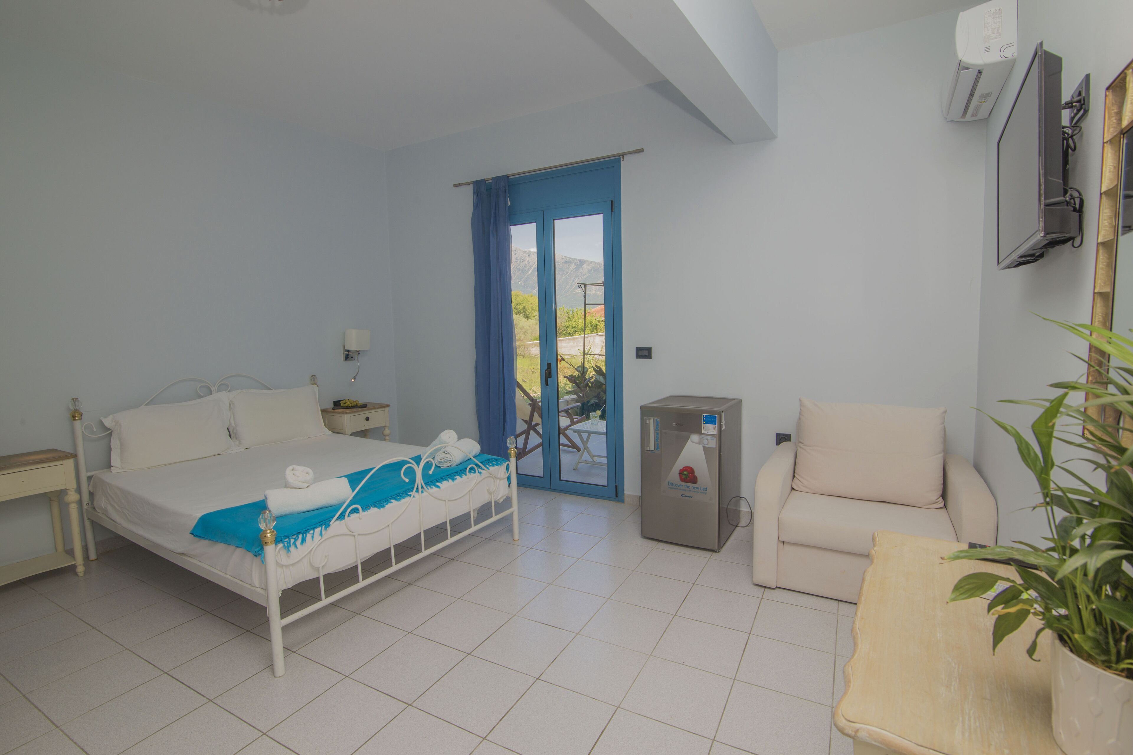 A bedroom with a bed, a chair, a small table, a radiator, and a door leading to an outdoor area.