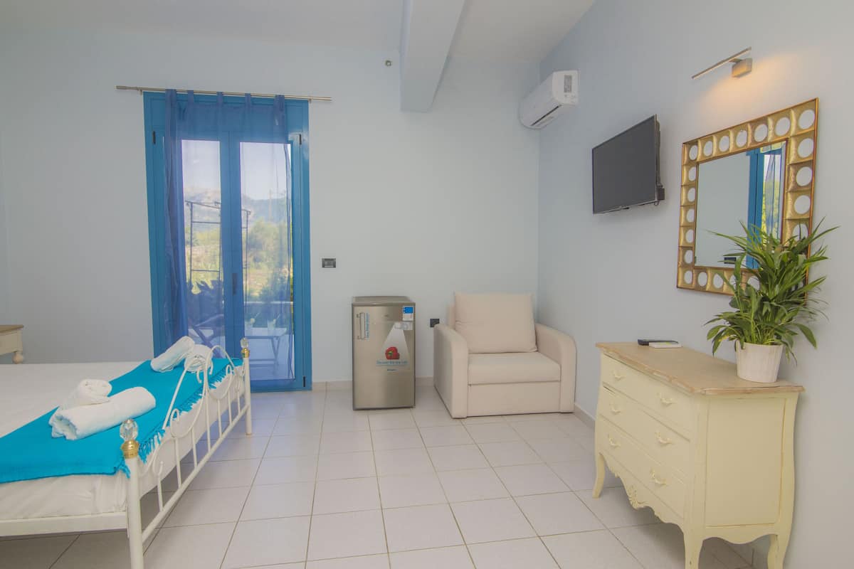 Una habitación de hotel con una cama, un escritorio pequeño, una silla, un aparador y una planta en maceta.