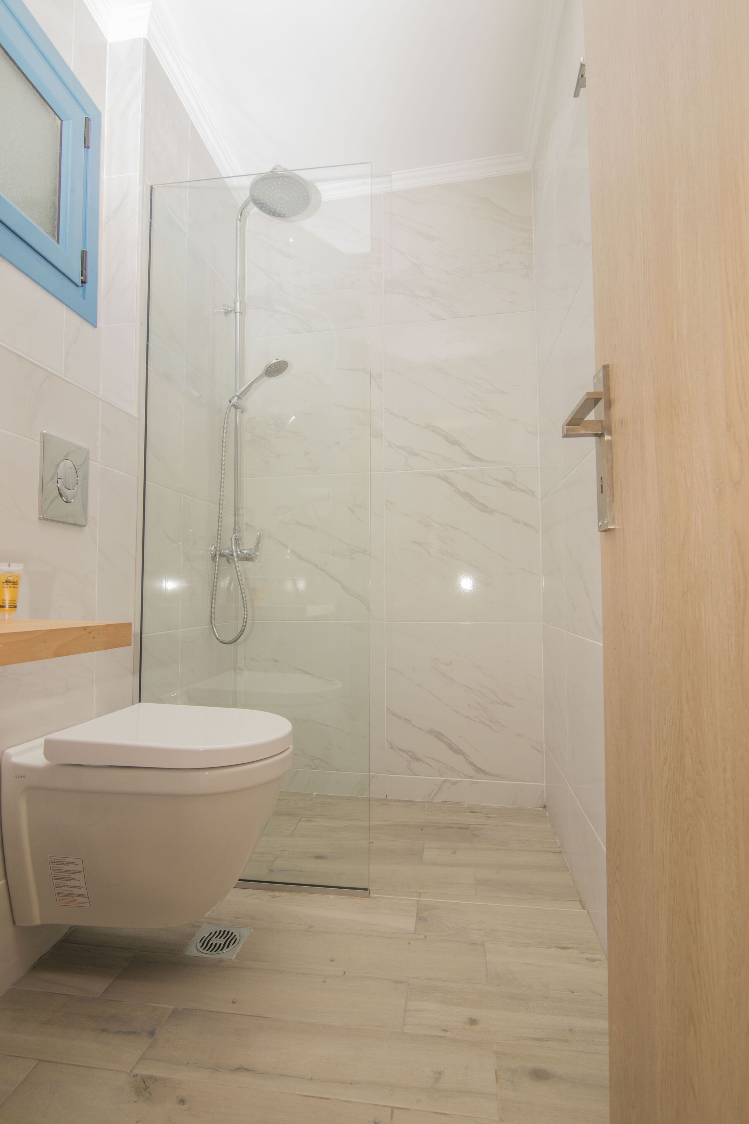 Une salle de bain moderne avec une douche à parois de verre, des toilettes blanches et un meuble-lavabo en bois.