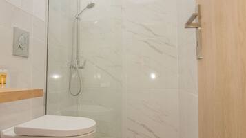 Une salle de bain moderne avec une douche à parois de verre, des toilettes blanches et un meuble-lavabo en bois.