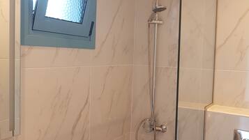 Une salle de bain moderne dotée d’une douche à parois de verre, d’un pommeau de douche à main et d’un robinet mural.