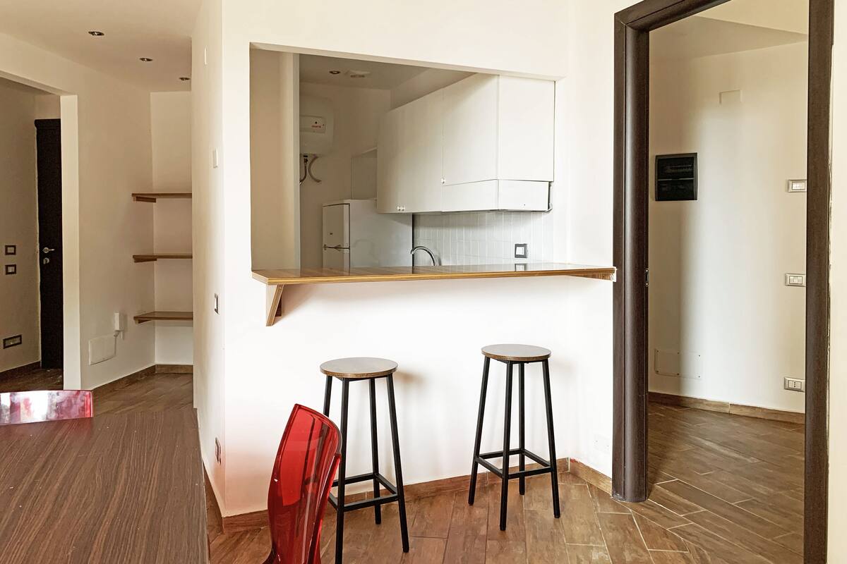 A modern kitchen with white cabinets, a wooden countertop, and two stools.