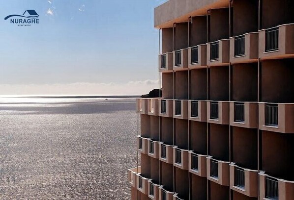 A modern building with a series of balconies overlooking a beach. - Nuraghe Apartments (Teulada)