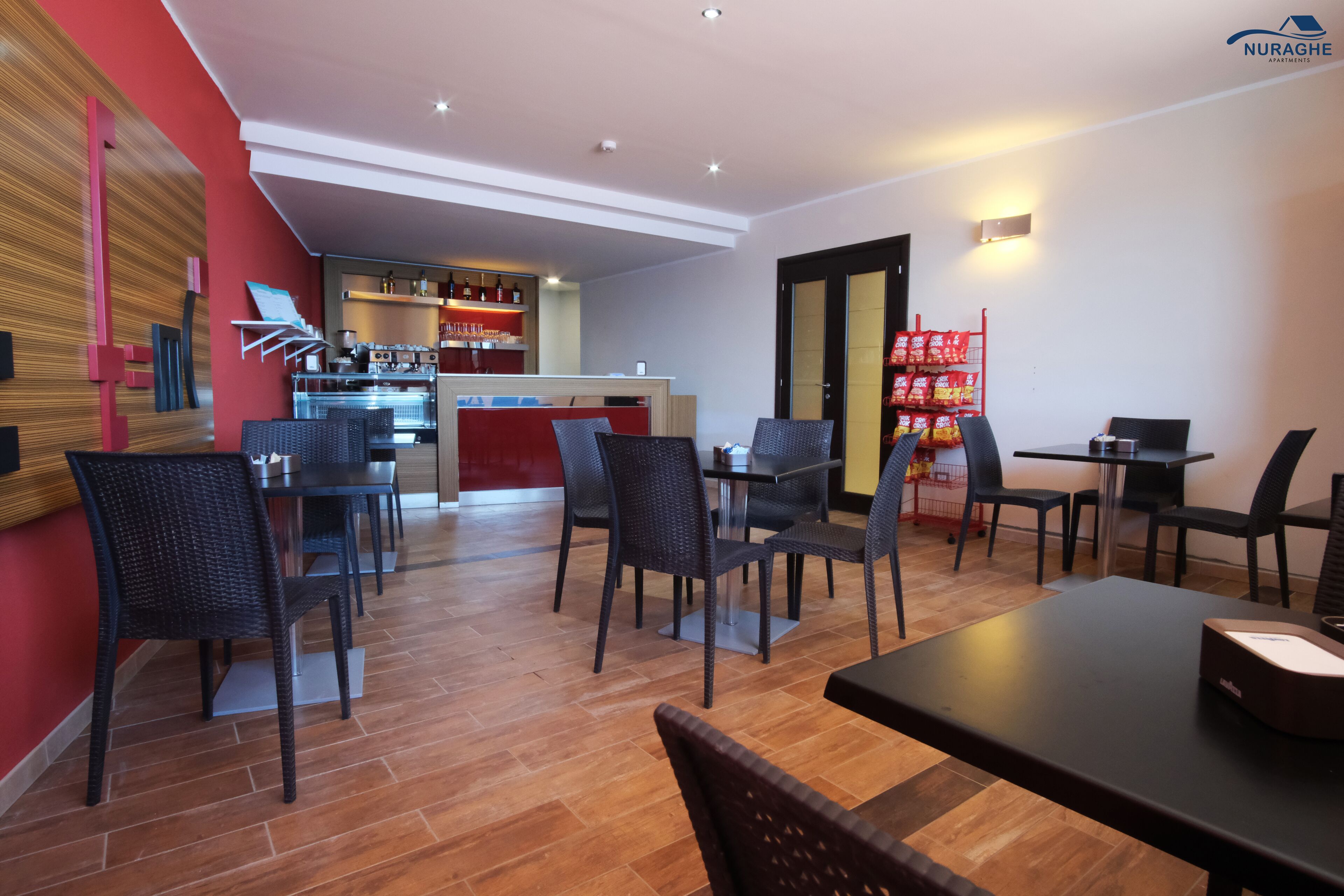 A modern dining area with a bar, black wicker chairs, and a wooden floor.