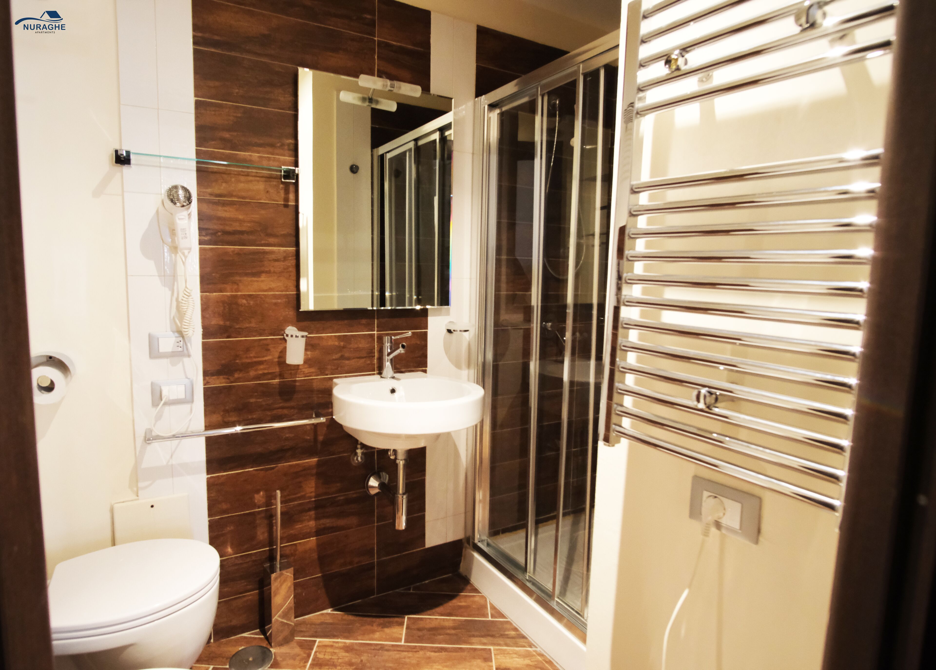 A modern bathroom with a white toilet, a sink, and a glass-enclosed shower.