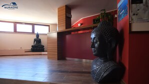 Una habitación con una estatua de Buda, estanterías de madera y una pared de acento roja.