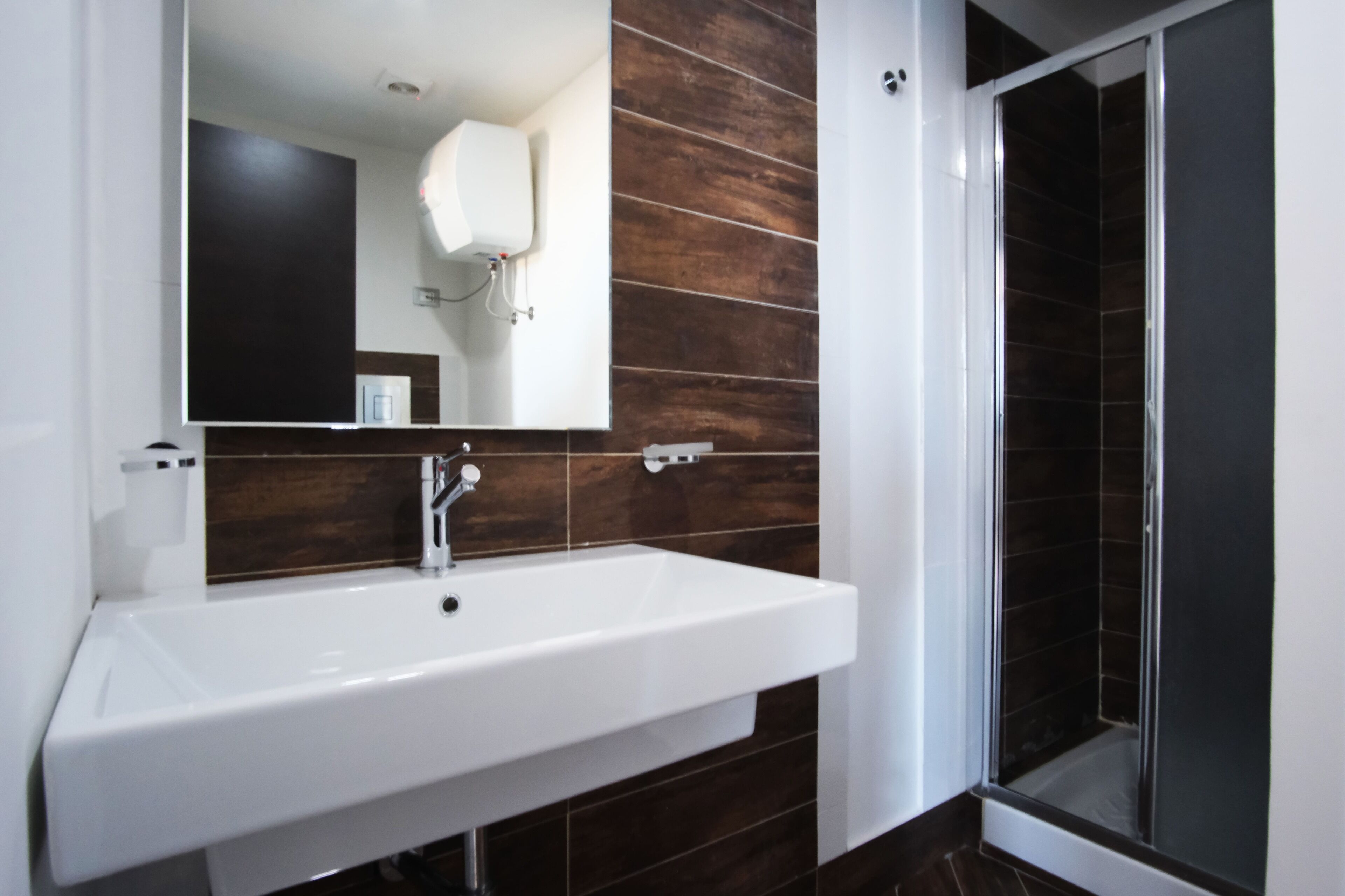 A bathroom with a white sink, a mirror, and a shower area.