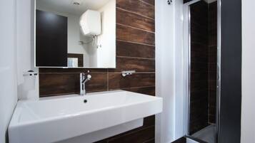A bathroom with a white sink, a mirror, and a shower area.