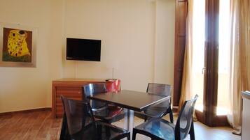 Een eethoek met een tafel en stoelen, een flatscreen televisie aan de muur en een schilderij.