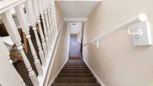 A staircase with white balusters and a carpeted landing. - Cecil Lodge - 2 Bed Apartment (Swansea)