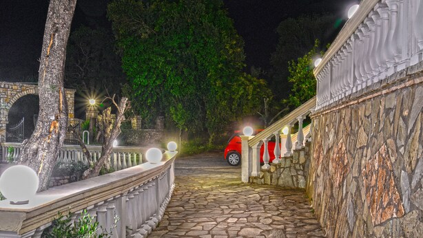 A stone pathway leading to a building with a red car parked outside. - Corfu Room Apartments,in a Lush Greeness Hill for Piecefull Holidays (Corfu)