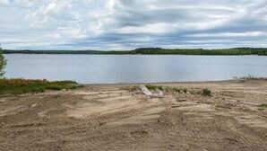 Une plage de sable avec un lac et des collines à l’horizon.
