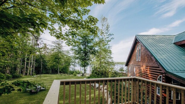 Une terrasse en bois offrant une vue sur un lac et une cabane en rondins.
