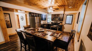 Une cuisine aux murs lambrés, avec une table à manger pour quatre personnes, équipée d’un réfrigérateur, d’un four à micro-ondes et d’une cuisinière.
