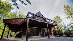 Une cabane en rondins dotée d’un porche couvert et de grandes portes-fenêtres coulissantes.