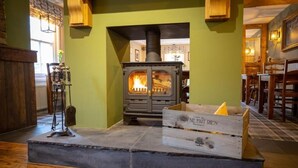 A cozy room with a wood-burning stove, a wooden chest labeled "CA NE FATT RIEN," and a rustic wooden bench.