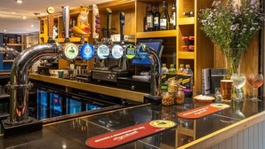 A bar area with multiple beer taps, a variety of bottles, and a flower vase.