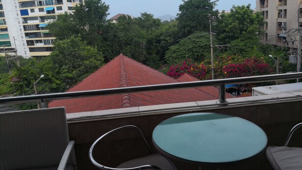 A balcony with a table and chairs, overlooking a cityscape with buildings and trees. - 305 Jomtien Hill Resort (Pattaya)