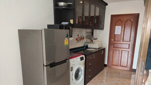 A compact kitchen with a stainless steel refrigerator, a washing machine, and dark wooden cabinets. - 305 Jomtien Hill Resort (Pattaya)