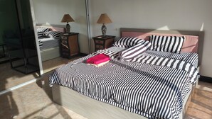 A bedroom with a bed, two nightstands, a mirror, and a sliding door. - 305 Jomtien Hill Resort (Pattaya)