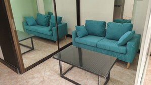A living room with teal sofas and a glass coffee table. - 305 Jomtien Hill Resort (Pattaya)