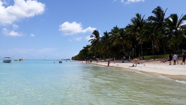 A beach with clear turquoise water, palm trees, and people enjoying the beach. - Residence Devika2 Trou aux Biches (Trou aux Biches)