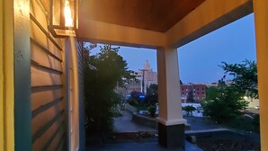 A covered porch with a view of a cityscape at dusk. - New Lower Rates! Amazing 8 Bedroom 3 Story Downtown Hot Springs! No Admin Fee!! (Hot Springs)
