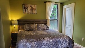 A bedroom with a bed, a nightstand, a lamp, a window with curtains, and a door. - New Lower Rates! Amazing 8 Bedroom 3 Story Downtown Hot Springs! No Admin Fee!! (Hot Springs)