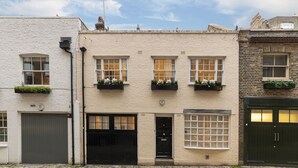 A row of traditional brick buildings with white facades, black doors, and flower boxes on the windowsills. - JOIVY Stunning 3BR house near Regents Park& Baker Street (London)
